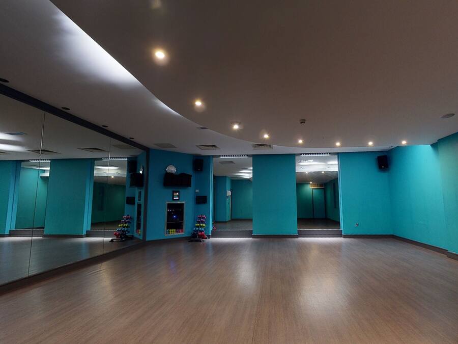 Una habitación amplia con paredes color turquesa, piso de madera y un espejo grande.