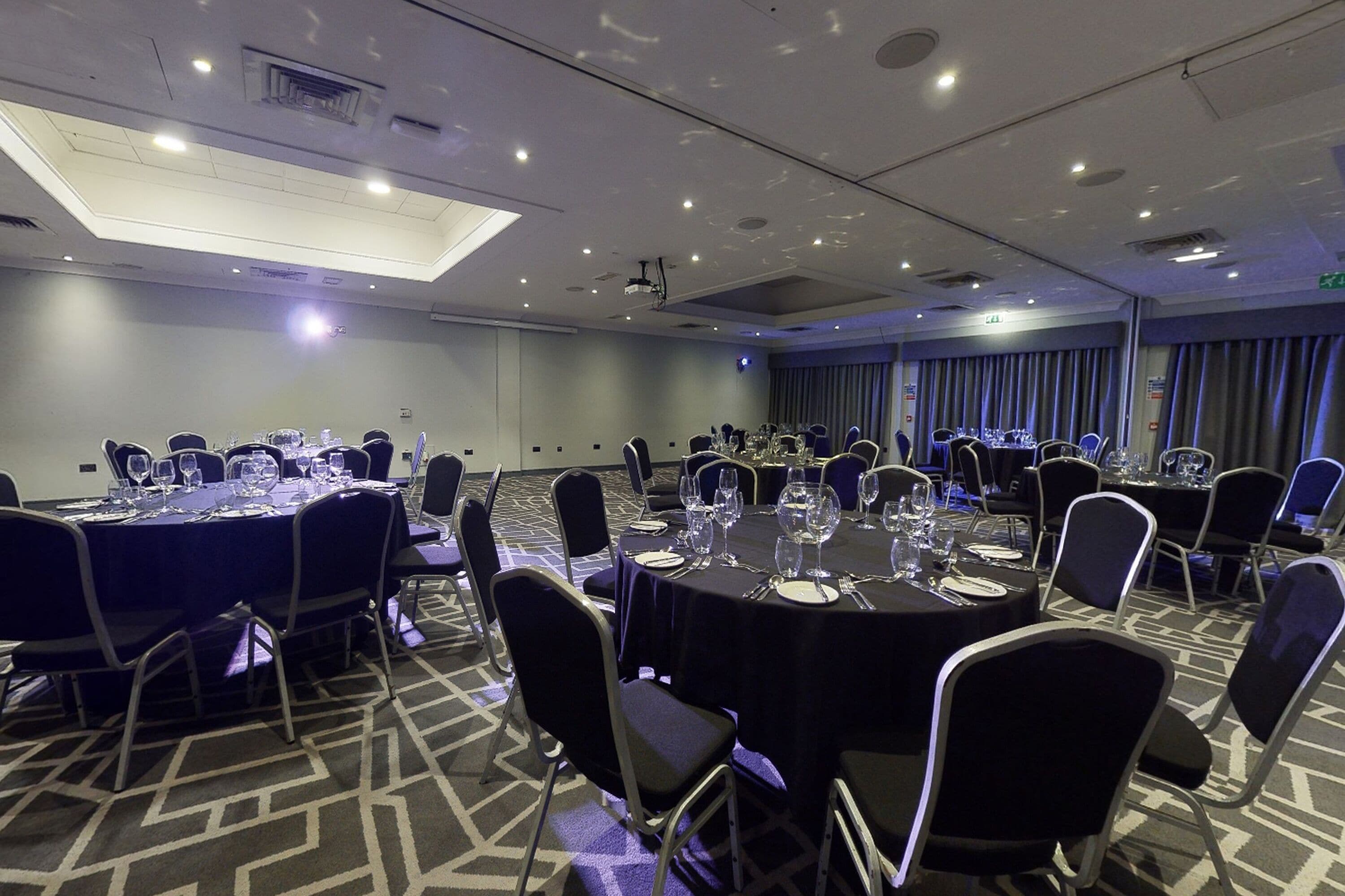 A conference room with round tables, chairs, and a ceiling light.