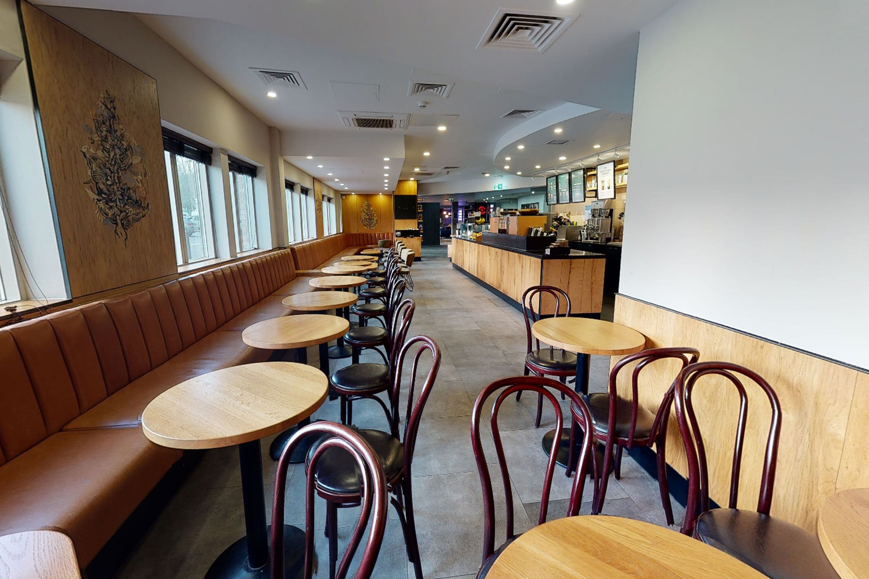 A restaurant interior with wooden booths, round tables, and metal chairs.