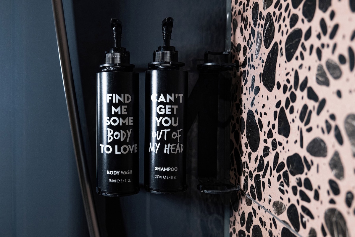 Trois bouteilles noires avec du texte blanc, accrochées à un mur.