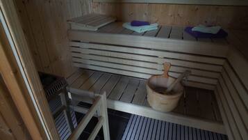 Una sauna de madera con bancos, un cubo de madera y una toalla.