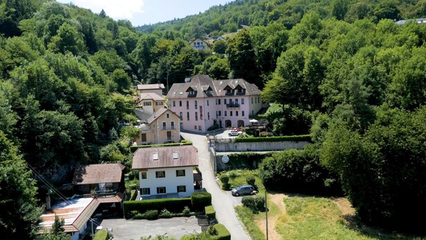 A hotel with multiple buildings, surrounded by lush greenery and hills. - Hotel des Marquisats Annecy (Annecy)