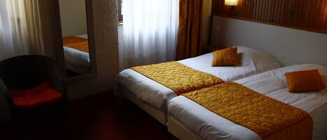 Habitación de hotel con dos camas, una silla y un espejo.
