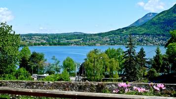 Une vue pittoresque d’un lac, avec une montagne en arrière-plan, entouré de verdure et un mur de pierre au premier plan.