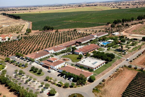 Vue aérienne d’un quartier résidentiel comprenant plusieurs maisons, une piscine et des champs agricoles environnants.