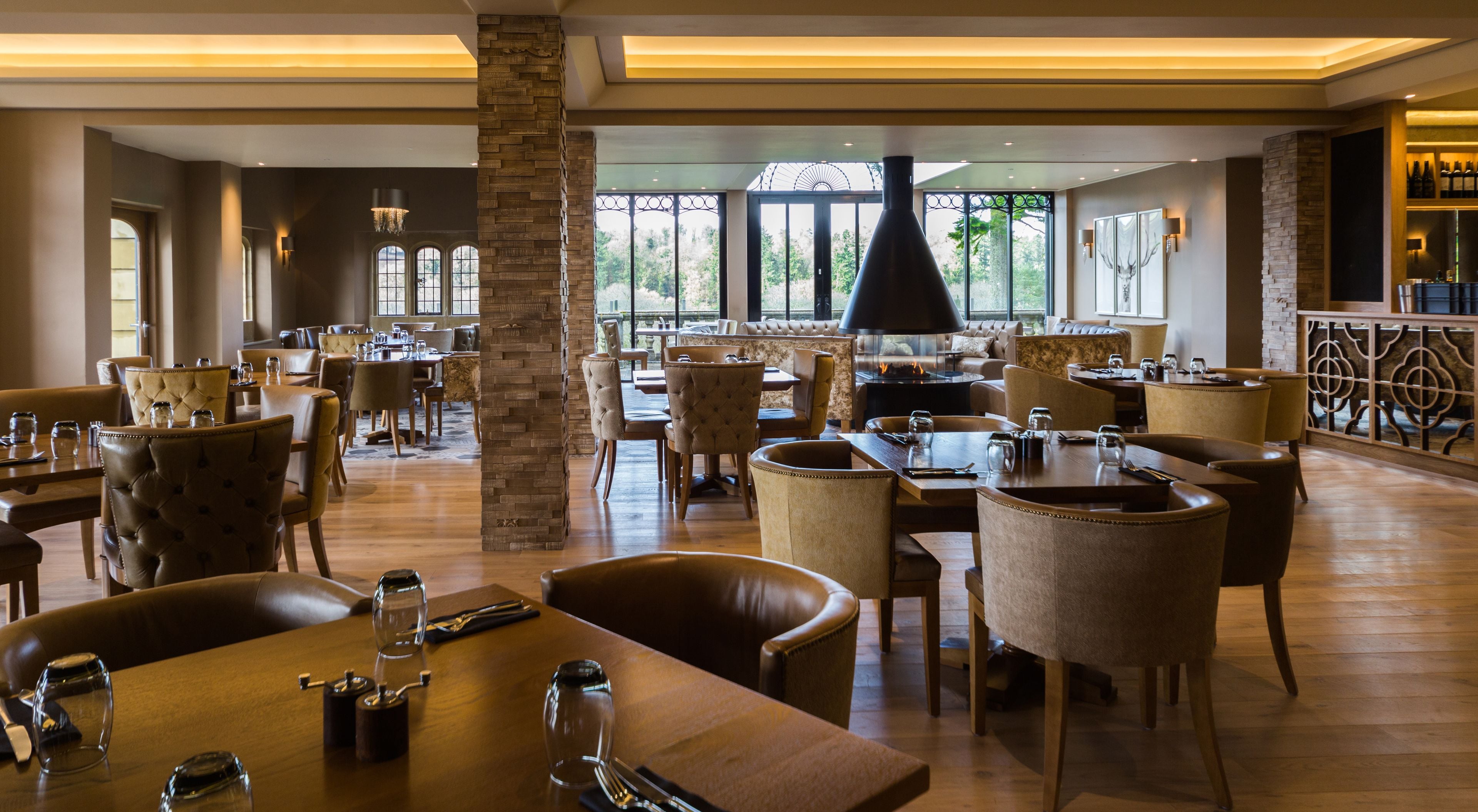 A spacious restaurant with multiple dining areas, a fireplace, and large windows offering a view of the outdoors.