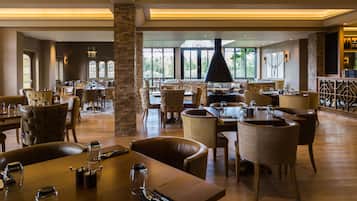 A spacious restaurant with multiple dining areas, a fireplace, and large windows offering a view of the outdoors.