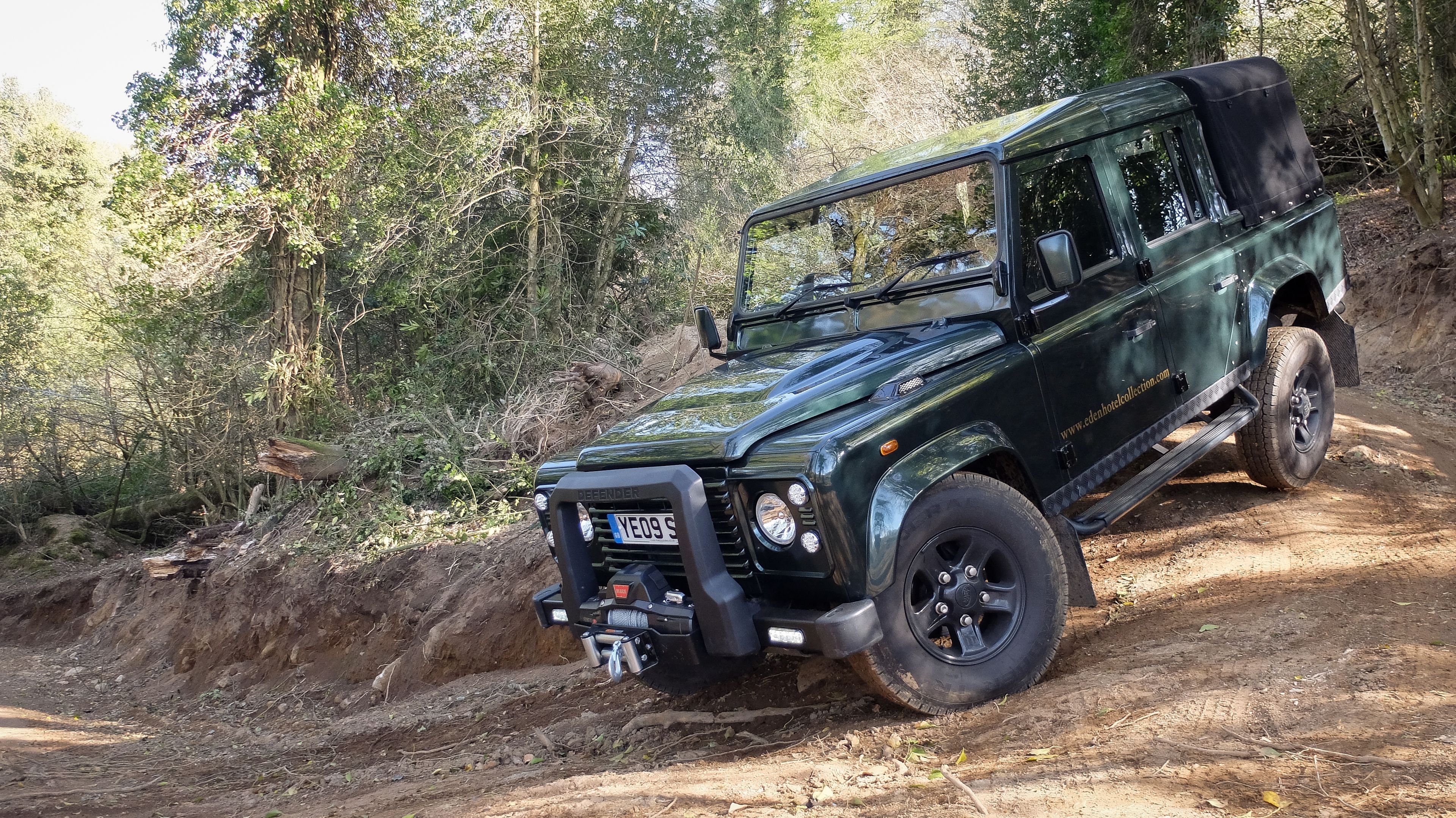 A black off-road vehicle on a dirt path surrounded by dense trees.