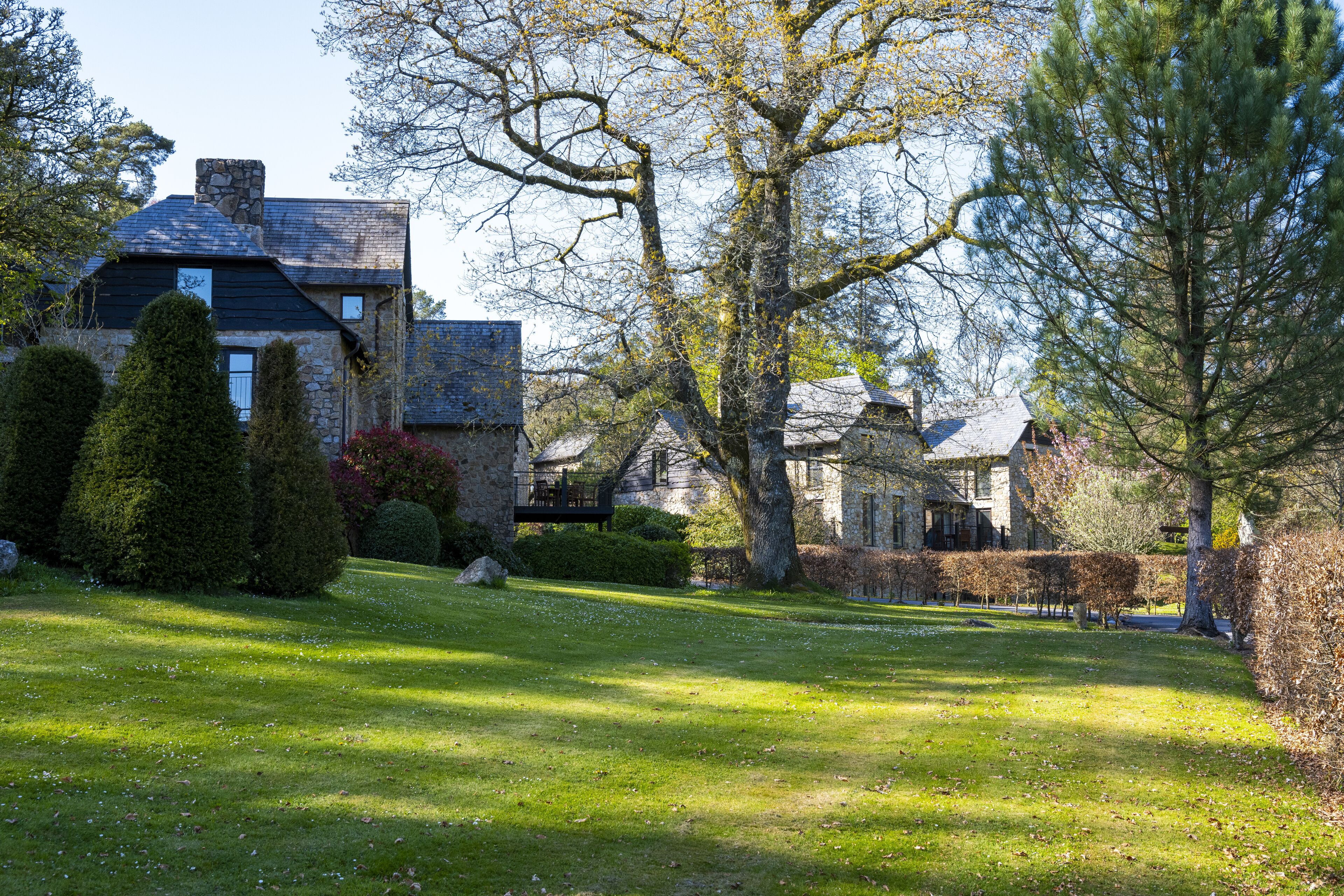 A stone house with a large lawn, a tree, and a well-maintained garden.