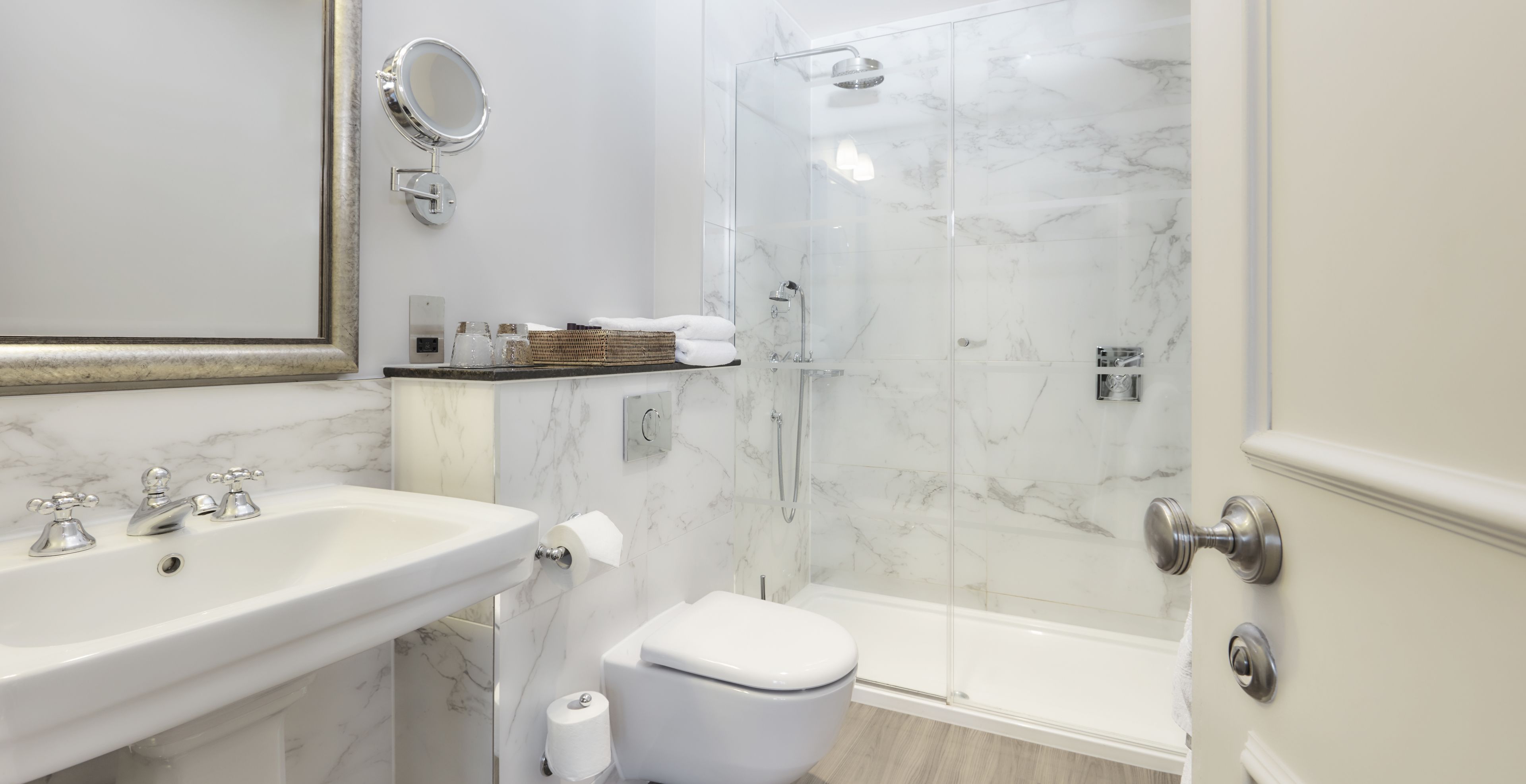 A modern bathroom with a marble sink, toilet, and shower.