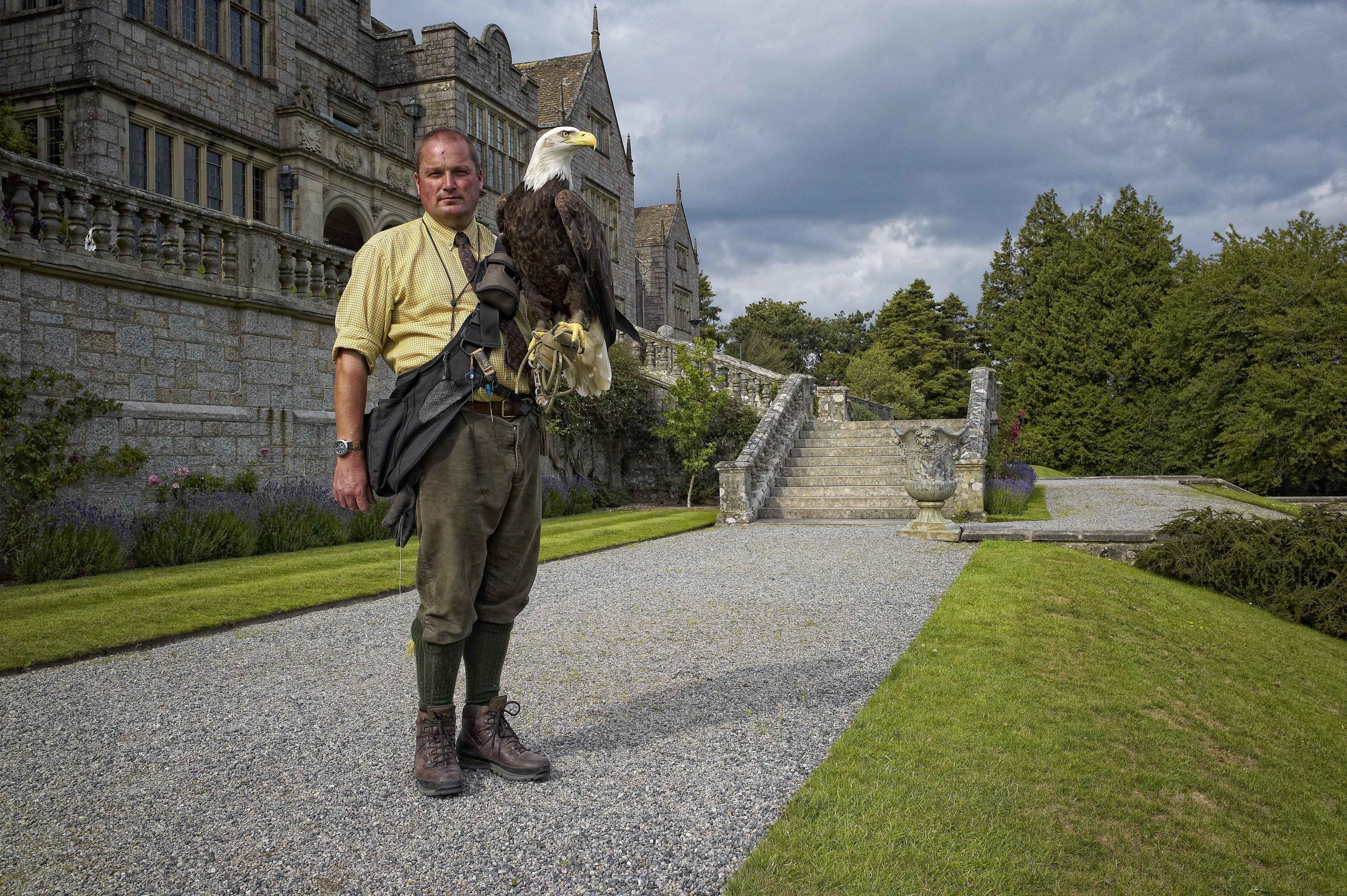 A man standing in front of a historic building with a bird perched on his shoulder.