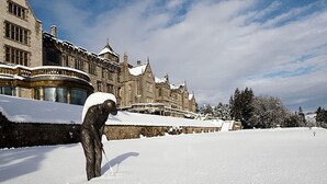 Ein großes, historisches Gebäude mit schneebedecktem Dach und einer Statue im Vordergrund.