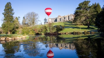 Un globo aerostático sobre un cuerpo de agua, con un edificio grande al fondo.