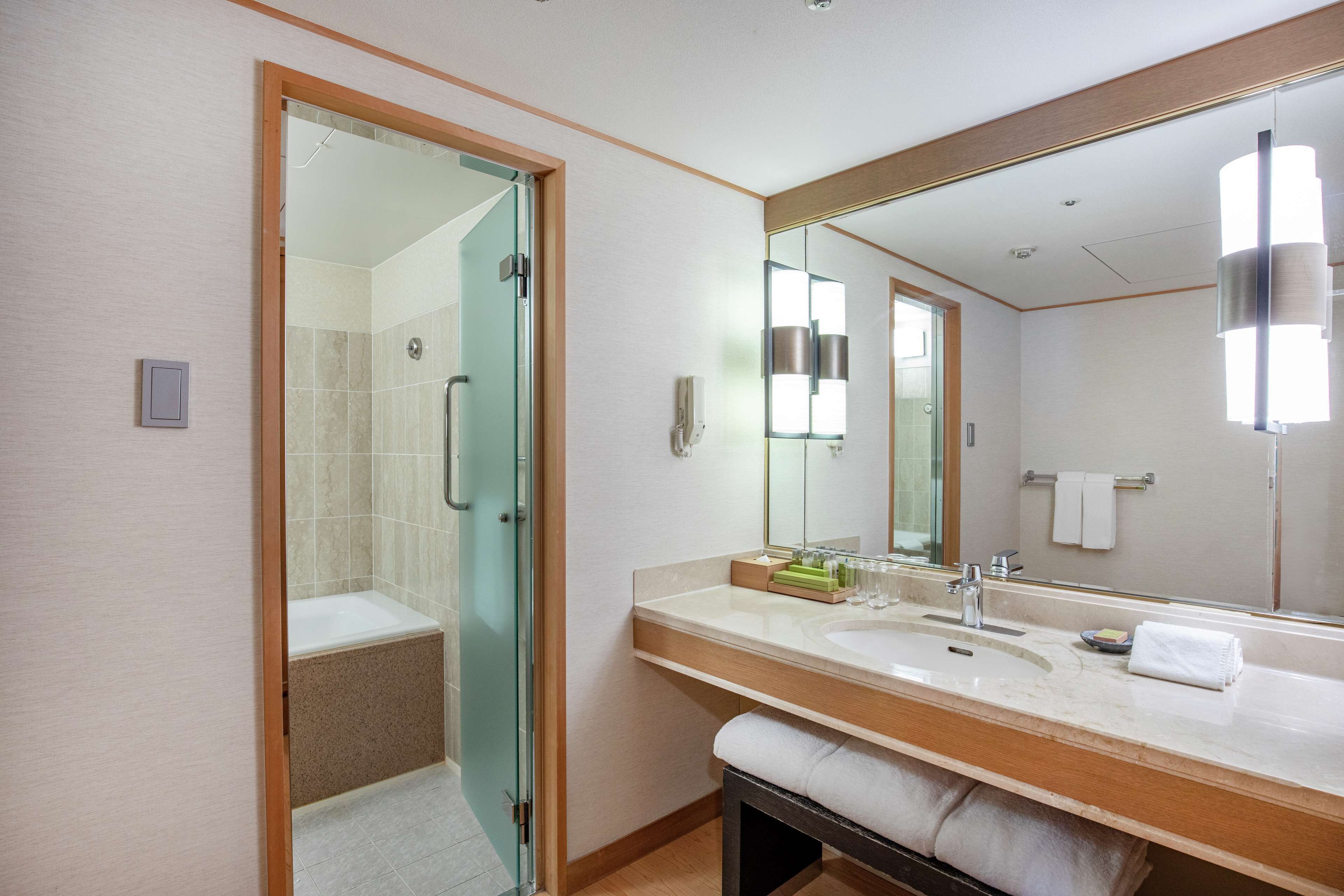 A modern bathroom with a glass shower enclosure, a large mirror, and a vanity with a sink and towel rack.