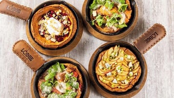 Four dishes served in cast iron skillets on a wooden table.