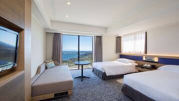 A hotel room with two beds, a TV, a balcony with a view, and a small table.