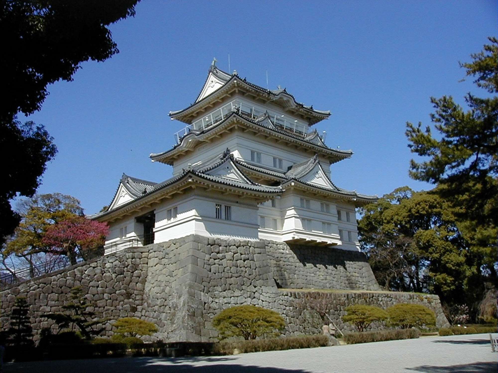 A traditional Japanese castle with multiple tiers, stone walls, and surrounding greenery.