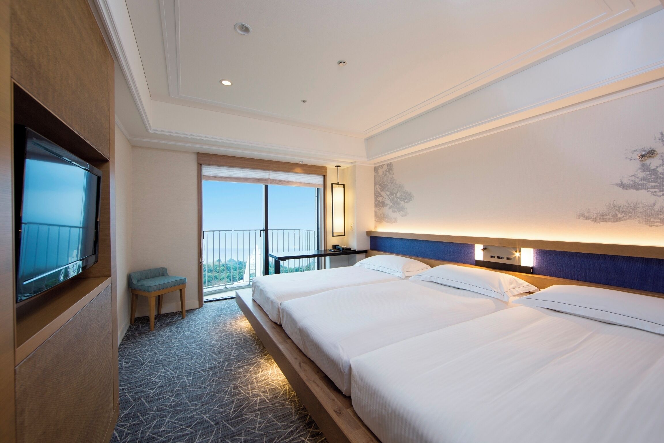 A hotel room with two beds, a TV, a balcony, and a large window.