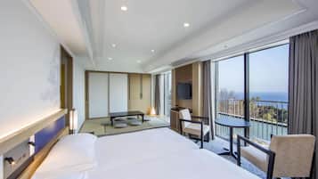 Ein Hotelzimmer mit einem großen Bett, einem Schreibtisch mit Stuhl, einem Fernseher und einem Balkon mit Blick.