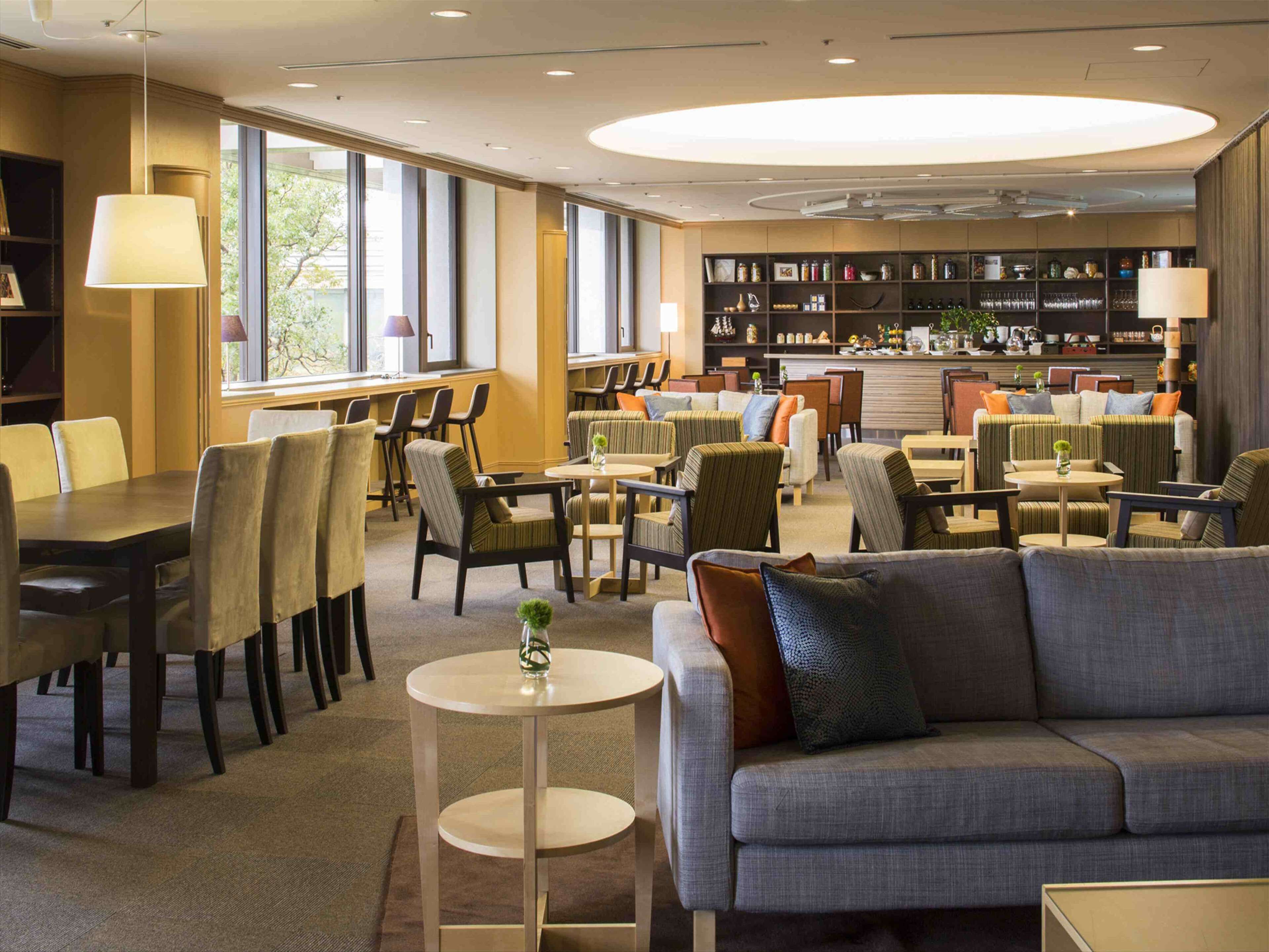 A modern hotel lobby with seating areas, a bar, and a bookshelf.