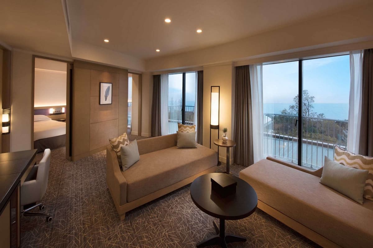 A hotel room with a sofa, a small table, a desk, and a bed.