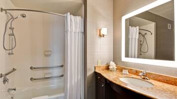A modern bathroom with a bathtub, shower, and vanity with a sink and mirror.