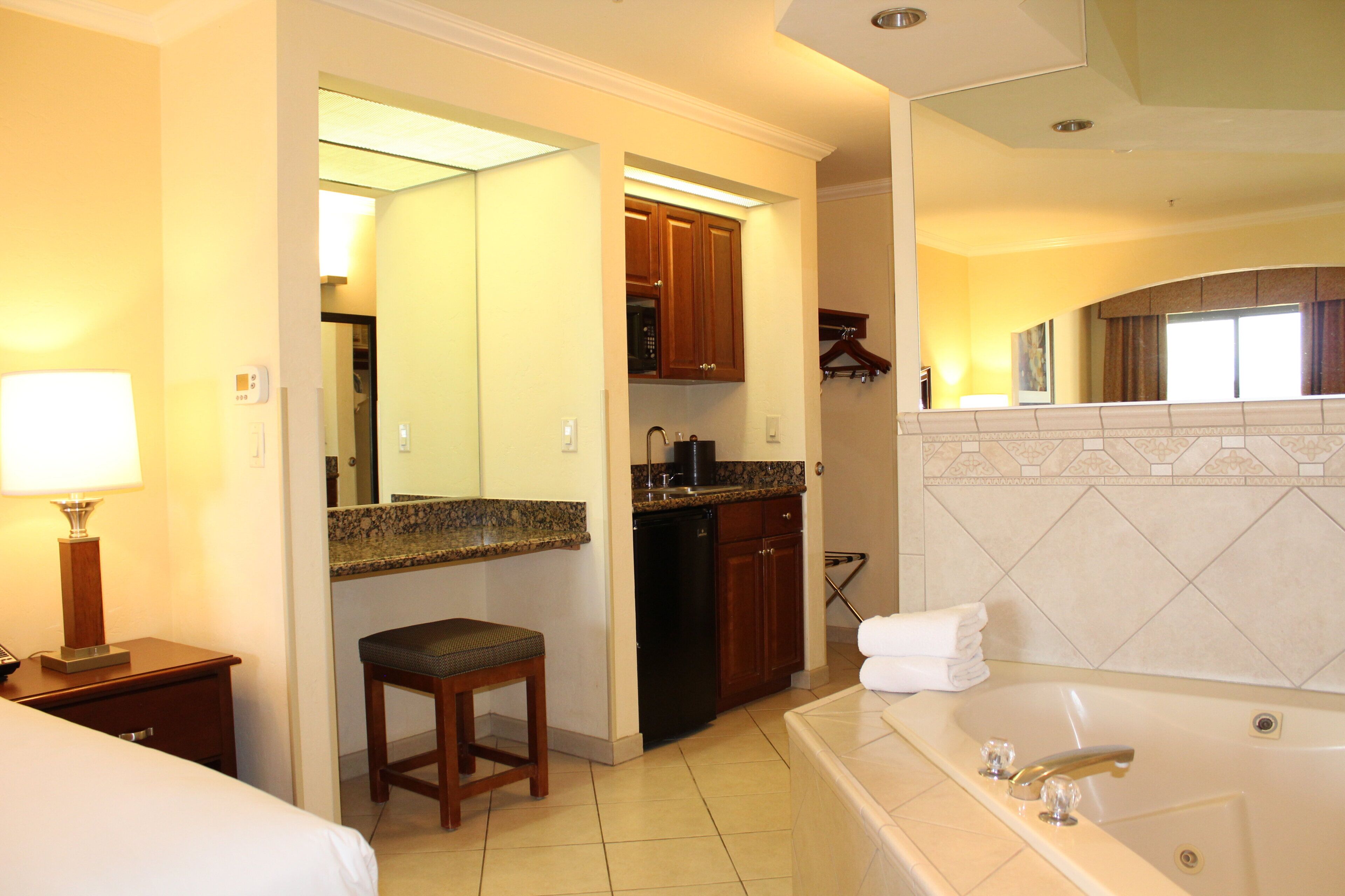 A hotel room with a large bathroom, a kitchenette, and a bed.