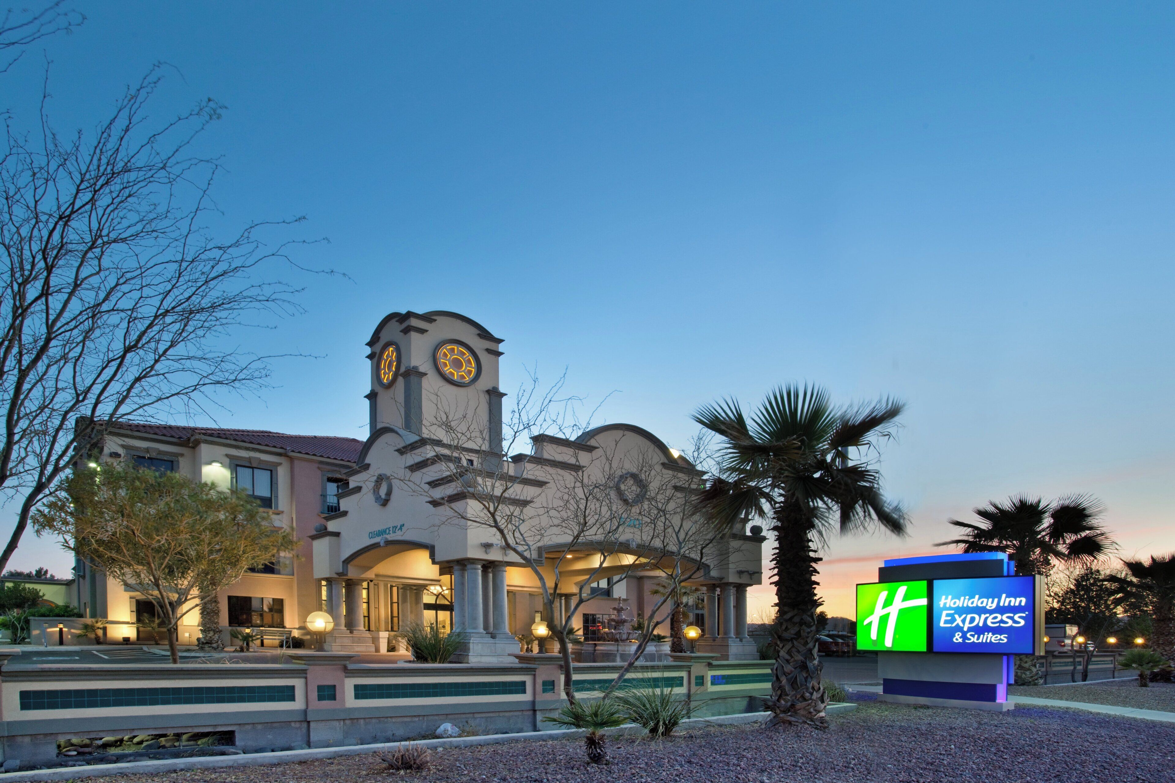 A hotel with a clock tower, a fountain, and a sign for Holiday Inn Express & Suites.