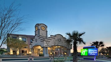 A hotel with a clock tower, a fountain, and a sign for Holiday Inn Express & Suites.