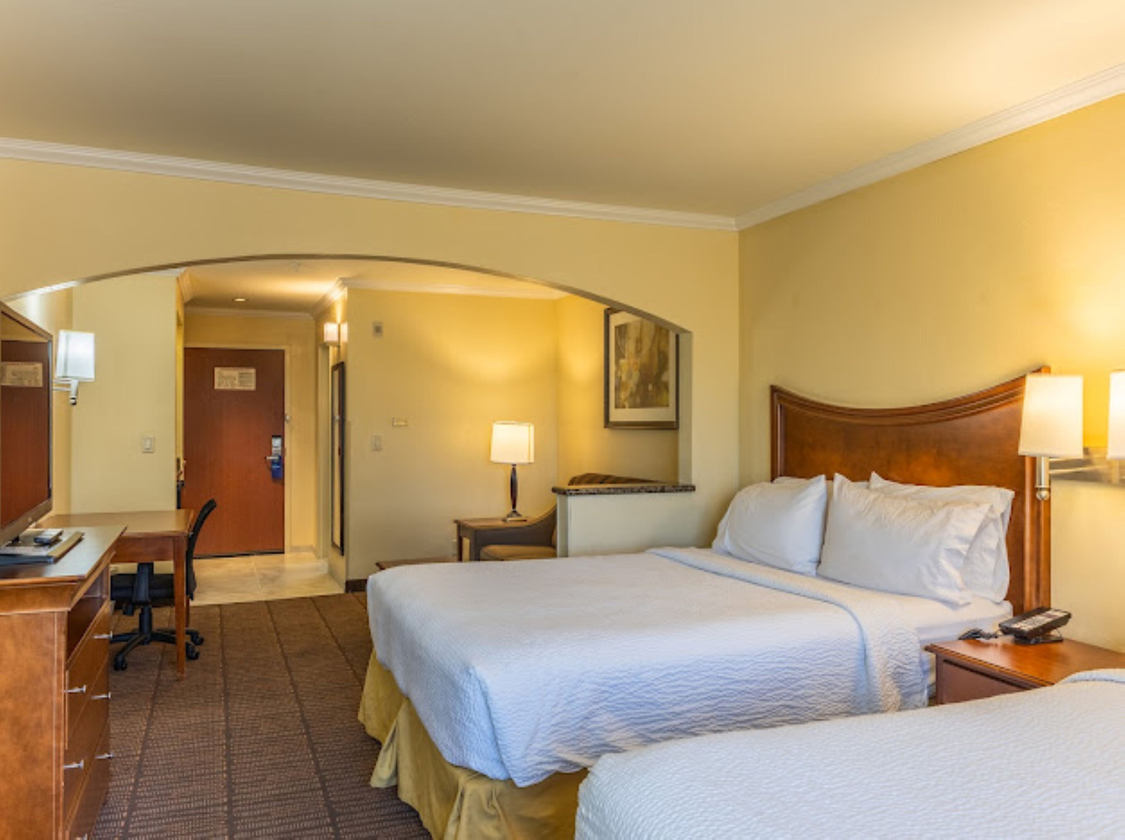 Habitación de hotel con dos camas, un escritorio y una silla.