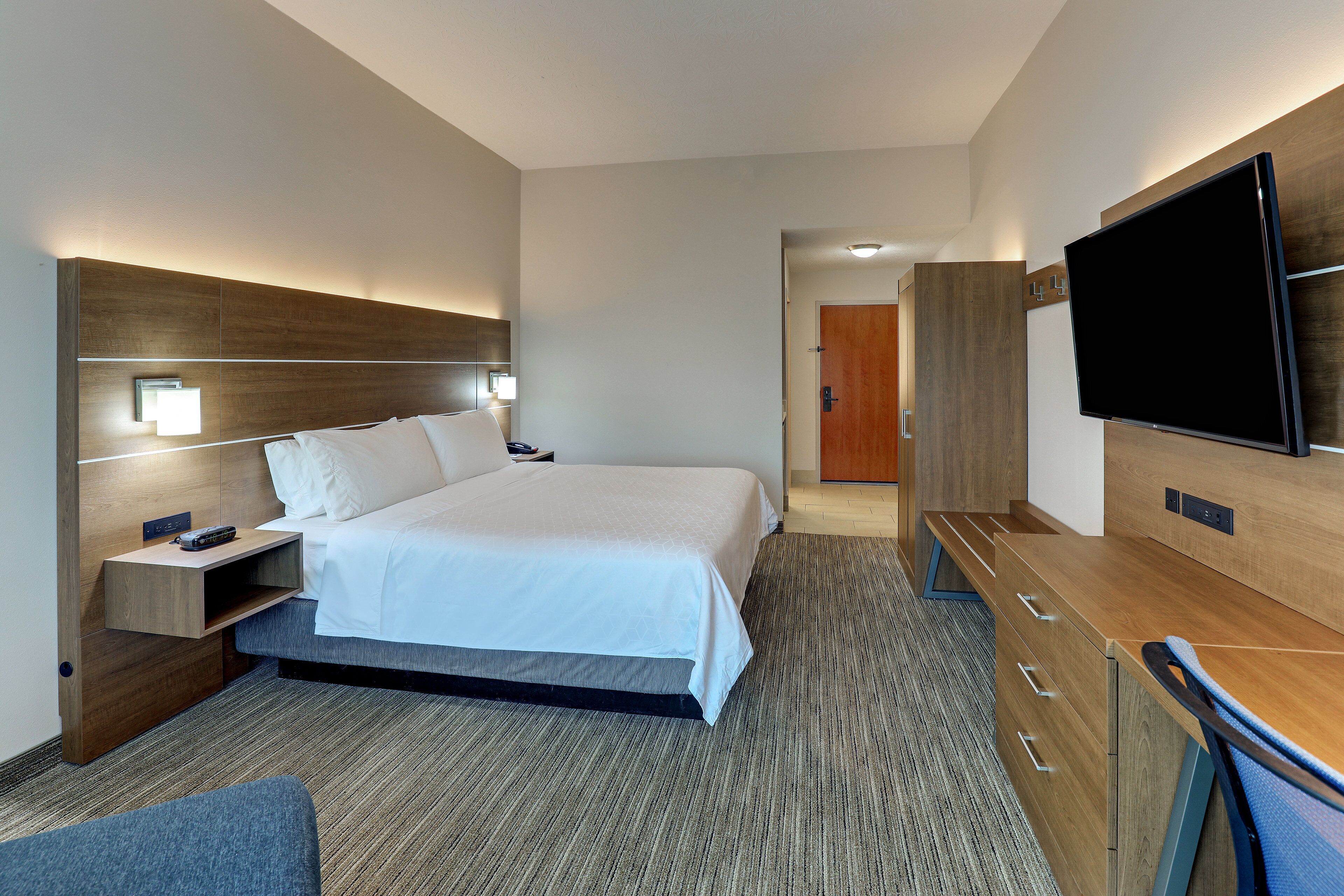 Une chambre d’hôtel comprenant un lit, des tables de chevet, un téléviseur à écran plat, un bureau avec des tiroirs et un sol recouvert de moquette.