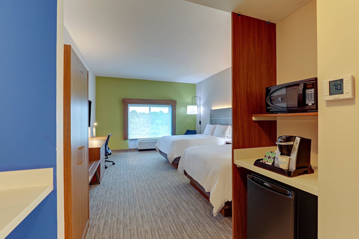 Habitación de hotel con dos camas, microondas, cafetera y refrigerador pequeño.