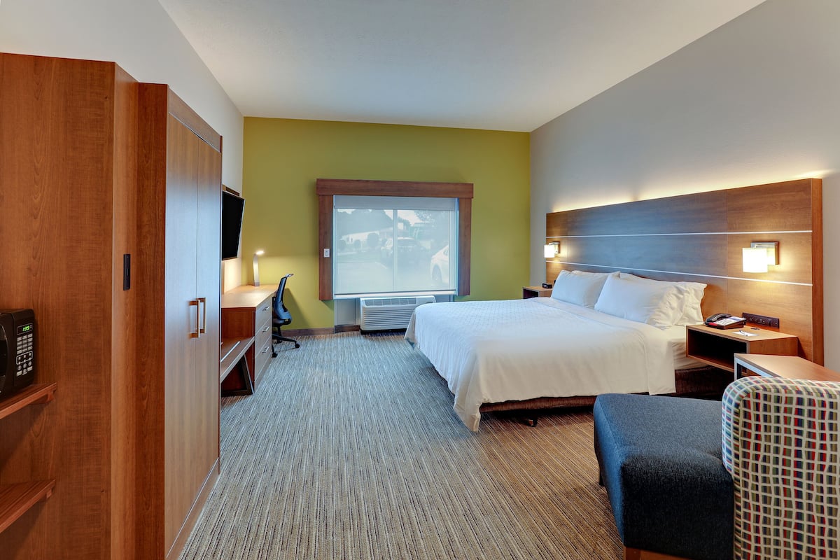 Una habitación de hotel con cama, mesita de noche, silla, escritorio y armario.