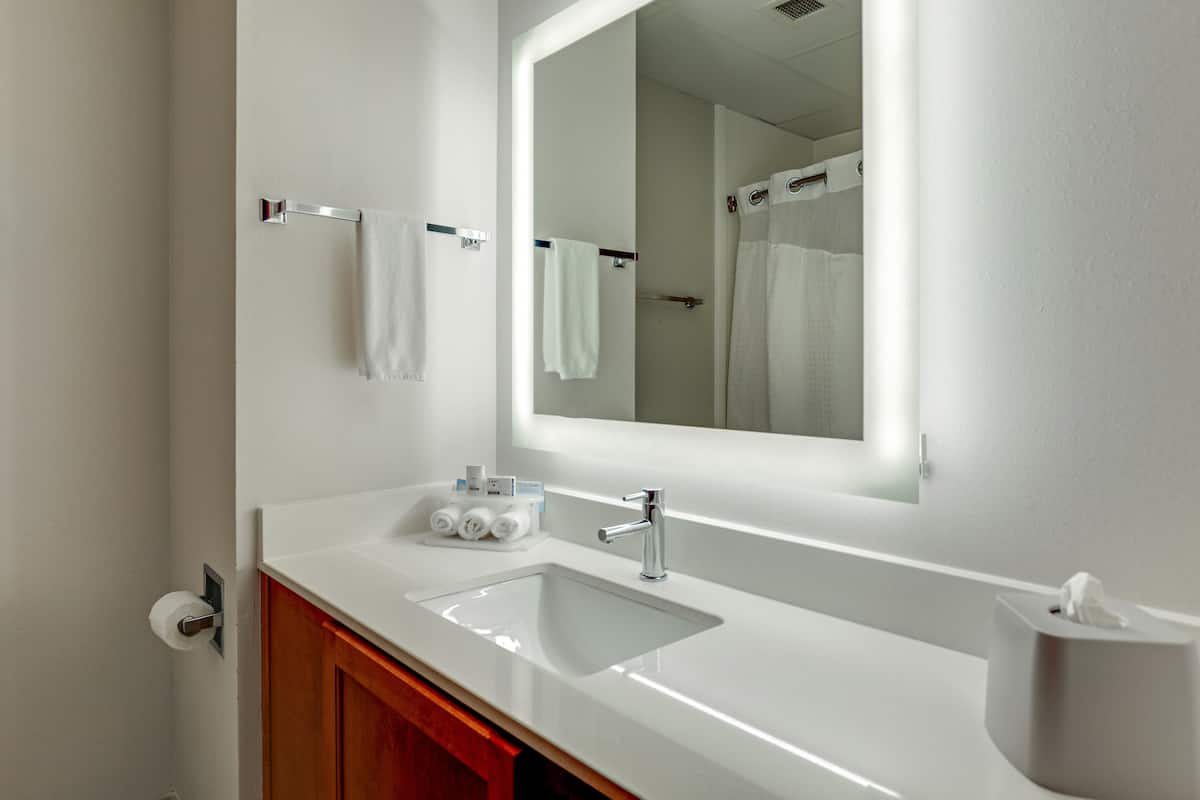 Un baño moderno con un lavamanos blanco, un espejo y una cortina de ducha.