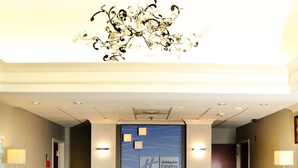 A hotel reception area with a wooden reception desk, a chandelier, and a wall-mounted sign for Holiday Inn Express.