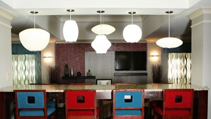 A modern kitchen with a large island, bar stools, and pendant lighting.