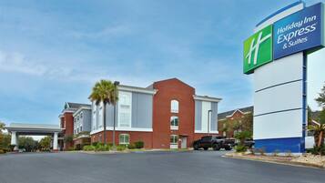 A Holiday Inn Express & Suites with a brick facade, a covered entrance, and a parking lot.