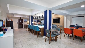 A modern hotel lobby with a reception desk, seating area, and a bar. - Holiday Inn Express Sumter by IHG (Sumter)