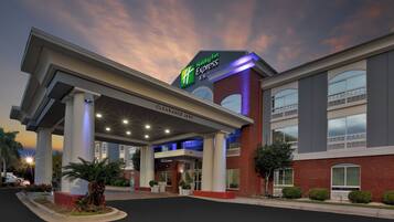 Welcome to the Holiday Inn Express & Suites, featuring a modern entrance with a covered canopy and adjacent parking area.