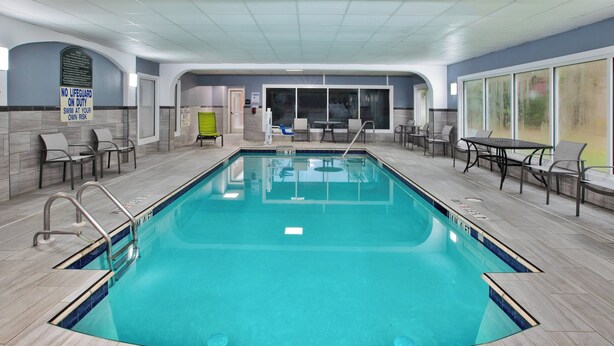 An indoor swimming pool with clear blue water, surrounded by tiled walls and a ceiling with a grid pattern.