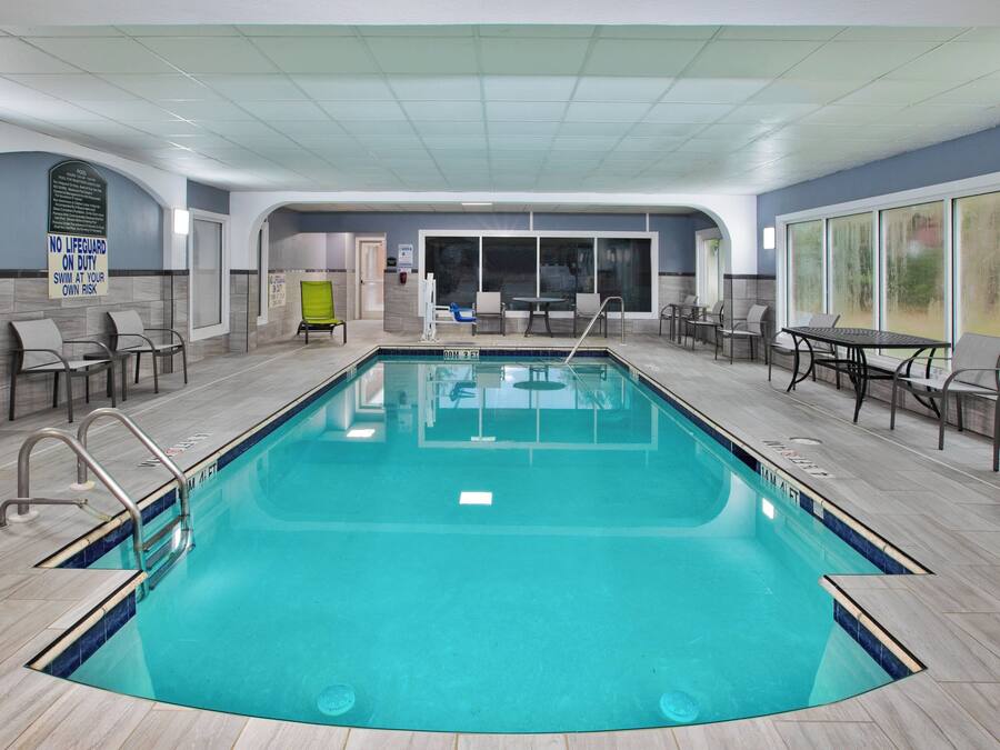 Una piscina interior con agua cristalina y paredes de azulejos, con techo de diseño de cuadrícula.