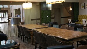 A restaurant with wooden tables and chairs, a bar area, and a green wall with a TV.