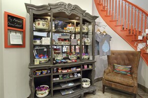 A china cabinet with various kitchen items and a chair with a colorful cushion.