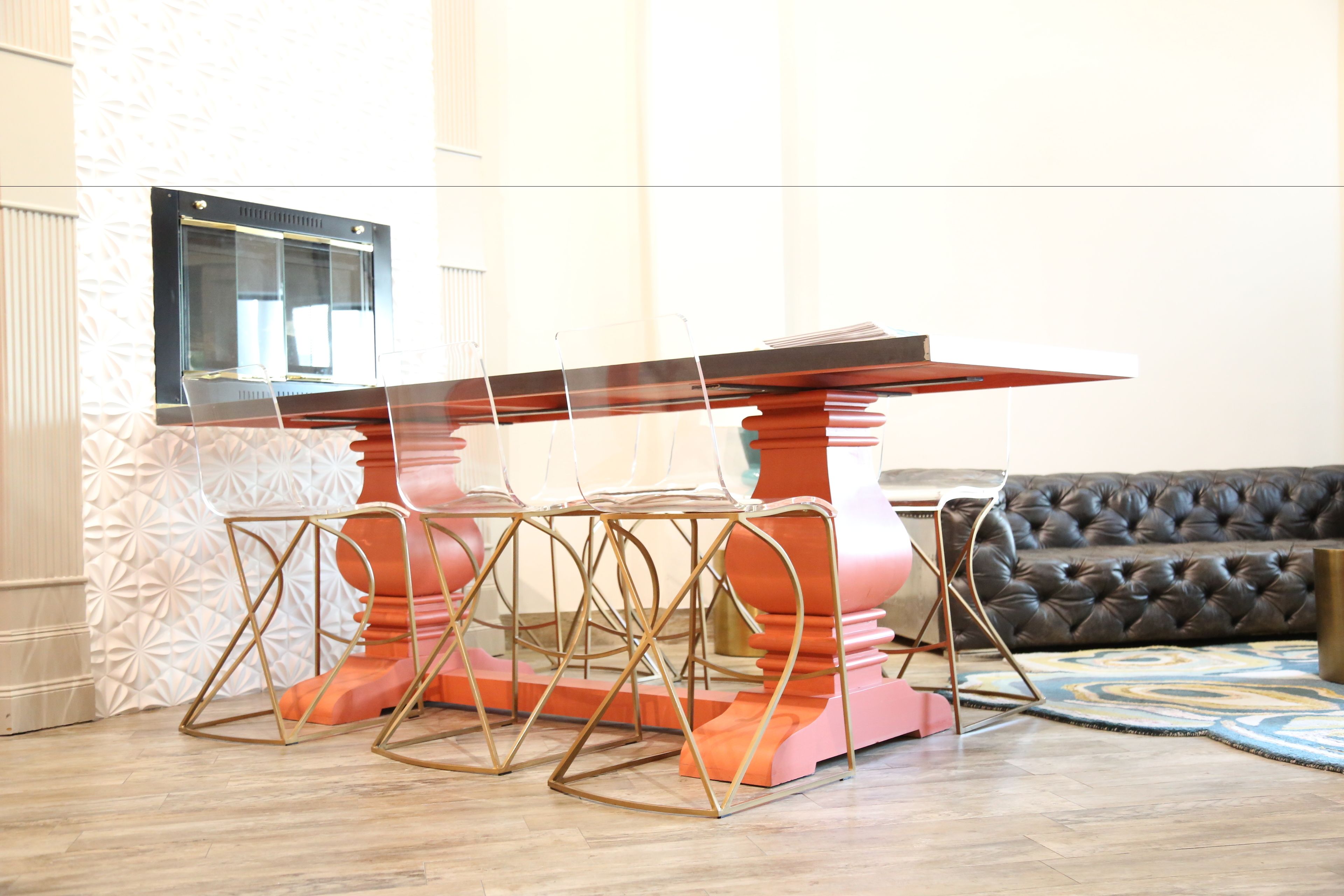 Un comedor moderno con una mesa de vidrio, patas metálicas y un papel tapiz estampado.