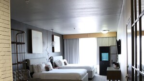 A hotel room with a bed, a desk, a chair, a TV, and a wardrobe.