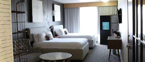 Una habitación de hotel con cama, escritorio, silla, televisor y armario.