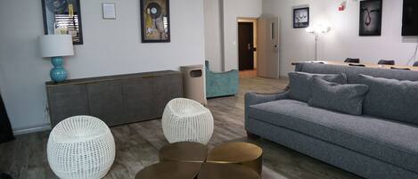 A modern living room with a grey sofa, white wicker ottoman, and a coffee table.