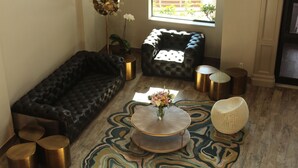 A living room with a black leather sofa, a round coffee table with a vase, and a patterned rug.