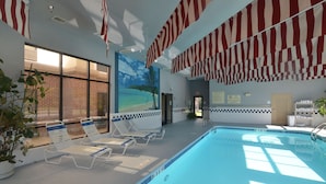 An indoor swimming pool with lounge chairs, American flags, and a mural of a beach scene. - Hampton Inn Ft Payne (Fort Payne)