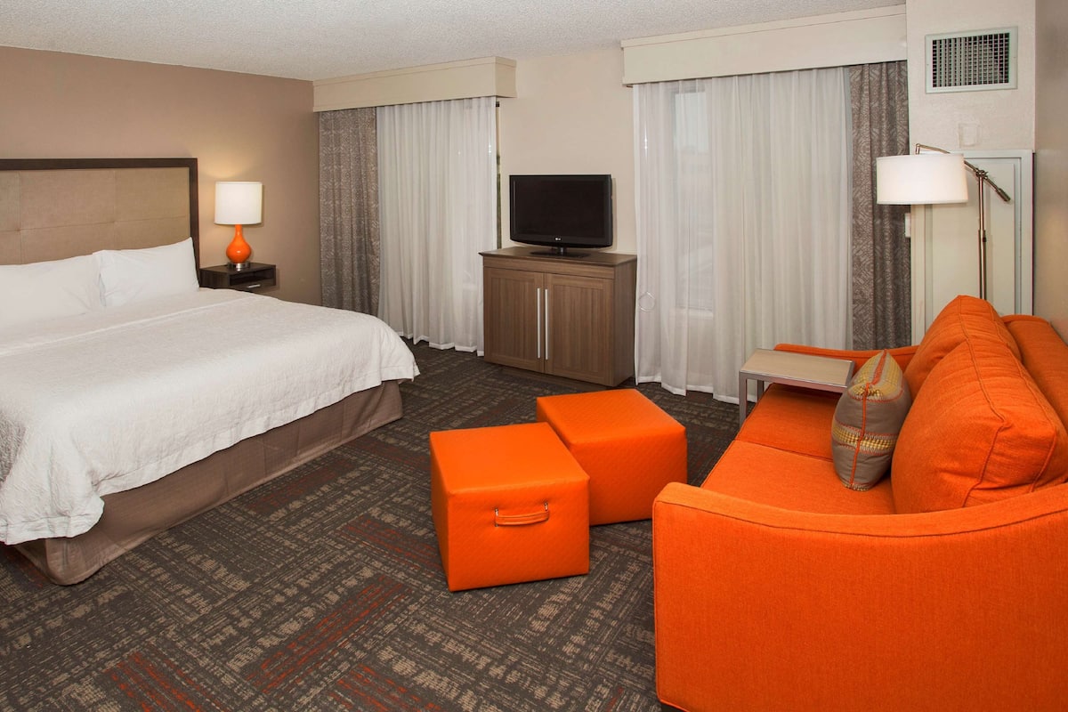A hotel room with a bed, a TV, a sofa, and a desk.